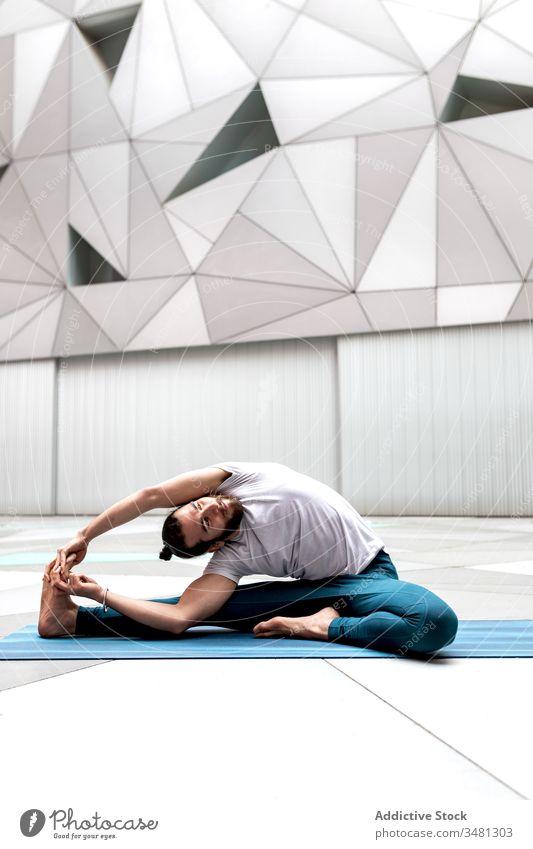 Flexibler Mann beugt sich beim Yoga-Training zum Bein Übung Geometrie gedrehte Kopf-zu-Knie-Haltung Wegbiegung modern Dehnung Fitness Form männlich
