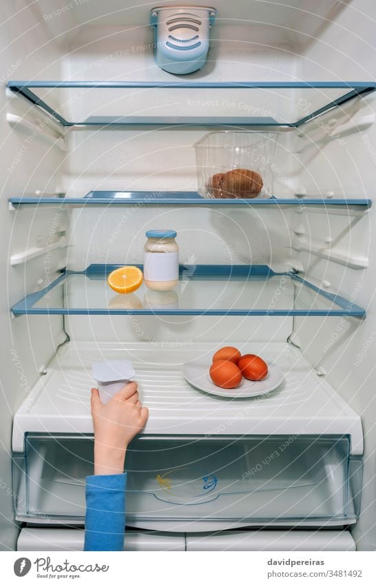 Mädchenhand nimmt den letzten Joghurt aus dem Kühlschrank Weltwirtschaftskrise Coronavirus unkenntlich Hand Kind hungrig kein Essen Küche Menschen heimwärts