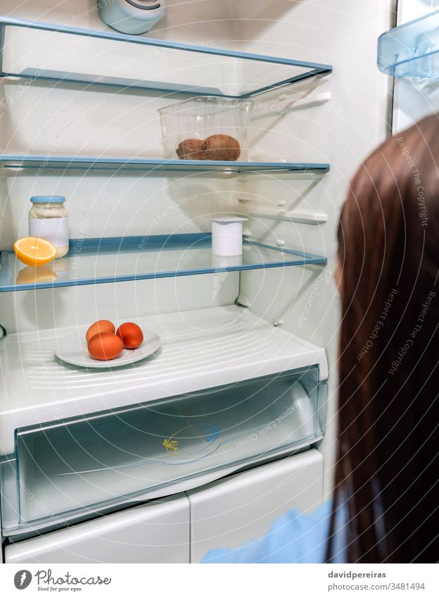 Mädchen schaut auf leeren Kühlschrank aufgrund einer Krise unkenntlich Blick leerer Kühlschrank covid-19 wirtschaftliche Probleme Coronavirus hungrig Armut