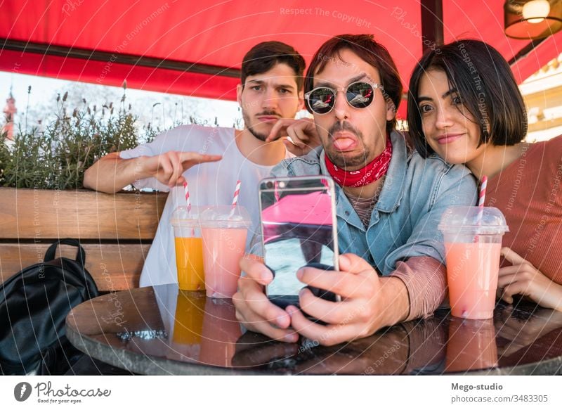 Drei junge Freunde beim Selfie mit Telefon. Glück Spaß Zusammensein Treffpunkt vier Freizeit Blick Person Sitzen Genuss Fröhlichkeit Smartphone Partnerschaft