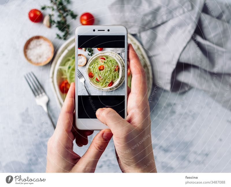 Zucchini-Nudelsalat. Draufsicht, Kopierraum Smartphone Fotografie Frau Hand Halt Telefon klug nehmen sozial roh Salatbeilage Nudeln zoodles Spaghetti Diät