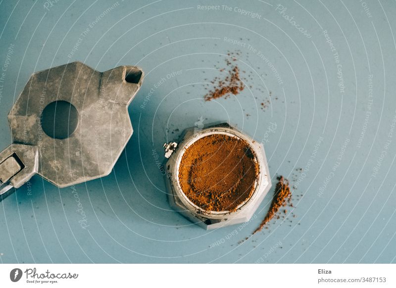 Ein Bialetti Espressokocher Kaffeemaschine Kaffeekocher mit Kaffee befüllt auf blauer Arbeitsplatte von oben bei der Kaffeezubereitung gemahlen Kaffeepulver