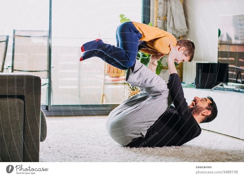 Vater und Sohn spielen zu Hause bezaubernd Air Baby Bonden Junge aufrichtiges Lachen Kind Spaß bei der Kinderbetreuung Kindheit Coronavirus covid-19 Papa