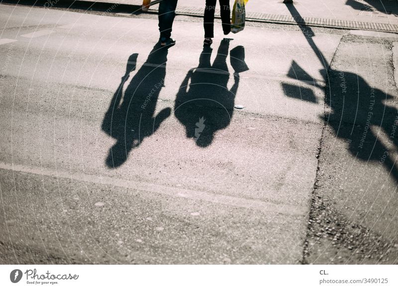 schatten von zwei personen auf der straße Fußgänger gehen Menschen Paar Bewegung Schatten Straße Schattenspiel Spaziergang spazierengehen Einkaufen