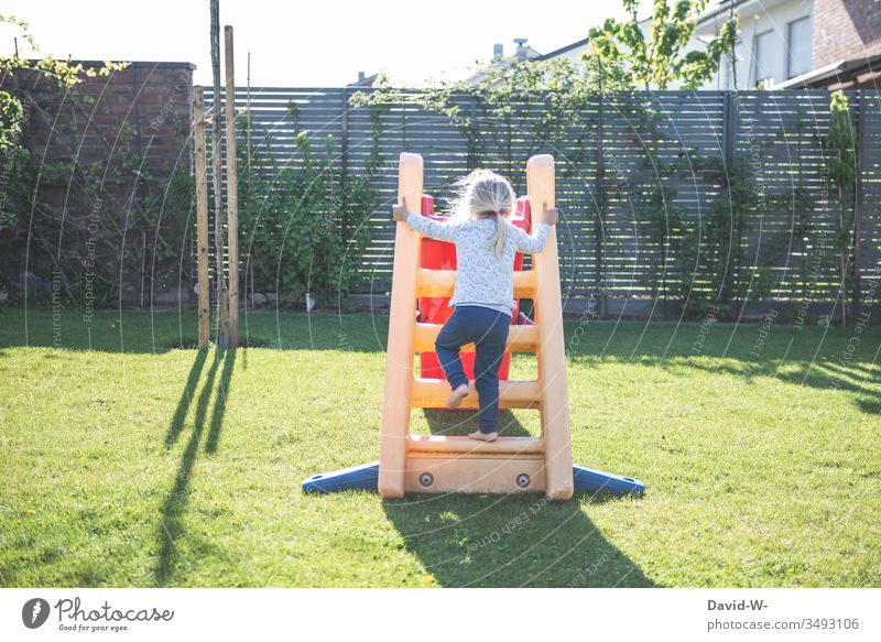 Kind klettert im Garten die Rutsche hoch spielen rutschen zu Hause Mädchen Spaß Freude Fröhlichkeit Lebensfreude