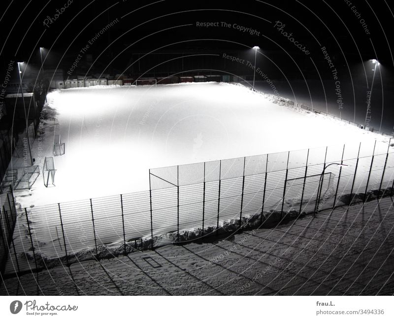 Geisterhaft menschenleer wurde der schneebedeckte Fußballplatz von fahlem Laternenlicht beleuchtet. Tore Winter Schnee Abend Licht