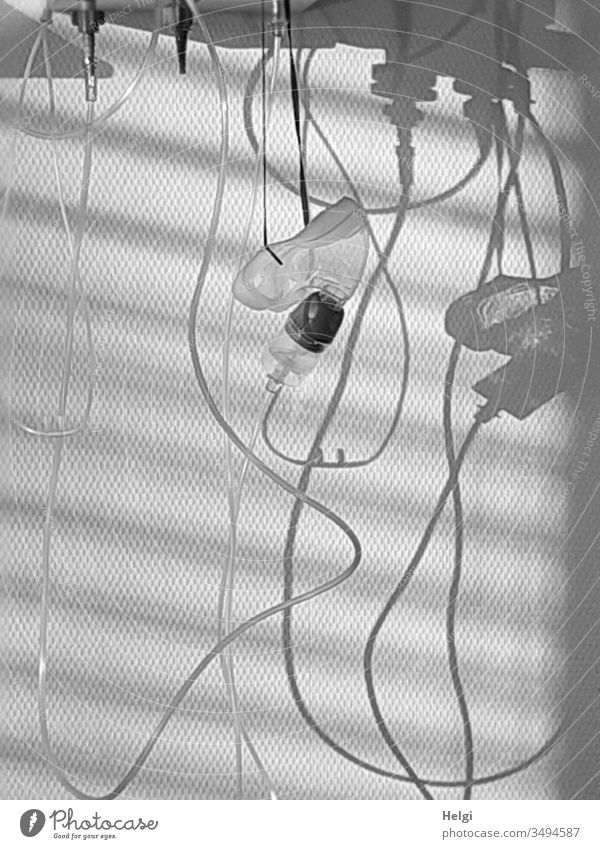 Inhalationsmaske und Sauerstoffschlauch hängen an einer Wand mit Licht und Schatten Schlauch Asthma Atemnot Krankheit Krankenhaus Krankenzimmer schwarzweiß