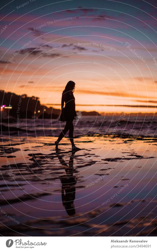 Silhouette einer jungen Frau an einer Meeresküste im Sonnenuntergang mit farbenfrohem Himmel und nassem Riff Dorf Sand Wellen Jugendliche Coolness Romantik