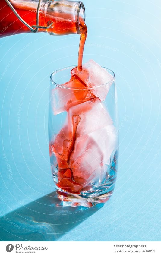 Erdbeersirup, der in einem Glas über Eiswürfel gegossen wird Beeren Getränk blau hell Nahaufnahme Cocktail kalt Erfrischungsgetränk farbenfroh Textfreiraum