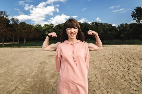 Sportlich-energetische athletische Frau trägt ein rosa Sporthöschen, das ihren Bizeps zeigt, sie mag Sport und einen aktiven Lebensstil. Athlet Muskel Fitness
