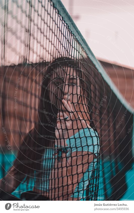 junge Frau, die sich an ein Tennisnetz lehnt Stil Farbfoto schön Junge Frau Farbe Mensch Porträt Phantasie Mysterium Licht Entwurf Studioaufnahme Körperkunst