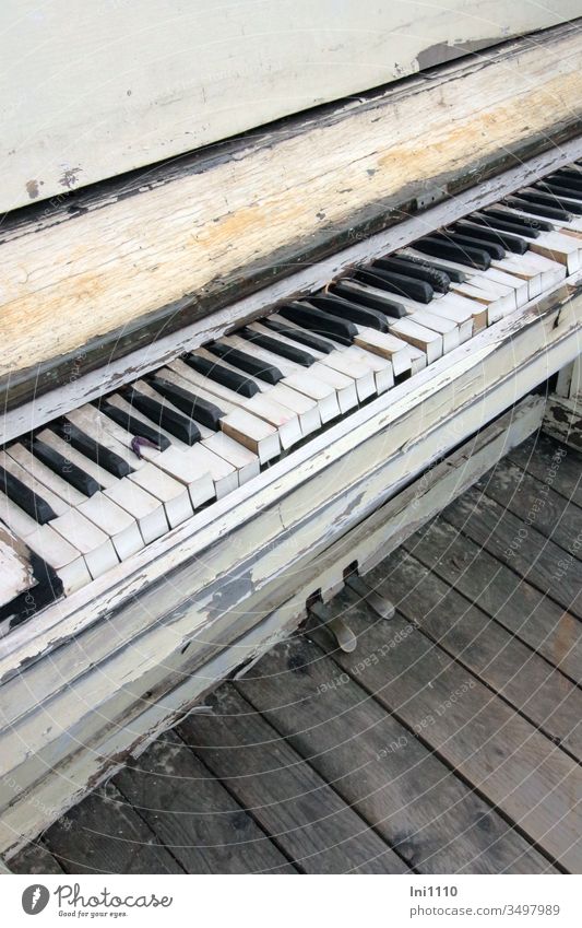 verwittertes altes Klavier steht auf verwitterten Holzplanken Sperrmüll Dekoration & Verzierung nostalgisch Hingucker ausgedient schwarz weiß Tasten Klaviatur