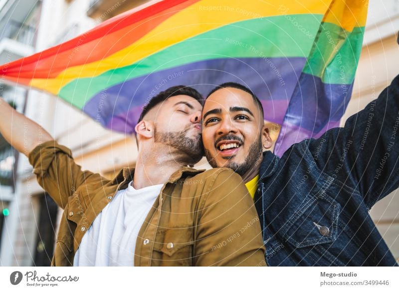Schwules Paar umarmt und zeigt seine Liebe mit der Regenbogenfahne. lgbt Fahne Homosexualität Freiheit schwul zwei Partner stolz Nähe außerhalb Vielfalt