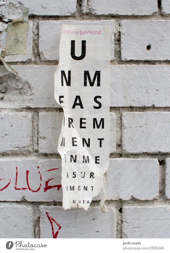 Zettel: Un measurement In measurement Typographie abstrakt Großbuchstabe Buchstaben Messung stabil Ziegelmauer weiß Fugen zerknittert angeklebt Sinn