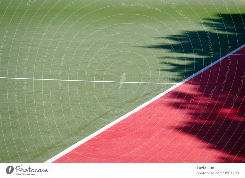 Spielfeld und Tartanbahn menschenleer im Sonnenlicht, mit viel Schatten Sportplatz Laufbahn Linien Gebüsch Geometrie Sonnenschein sonnig grün rot weiß