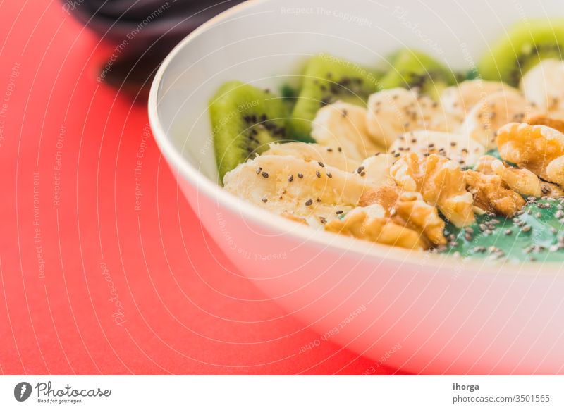 Spirulina-Smoothie-Schale mit Banane, Walnüssen, Kiwi- und Chiasamen auf rotem Hintergrund Antioxidans Schalen & Schüsseln Frühstück Nahaufnahme Farbe lecker