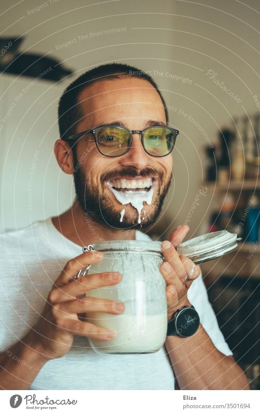 Ein Mann freut sich über seinen selbstgemachten Kefir voller Proteine so sehr, dass er beim Trinken nur Quatsch macht und sich bekleckert kleckern albern