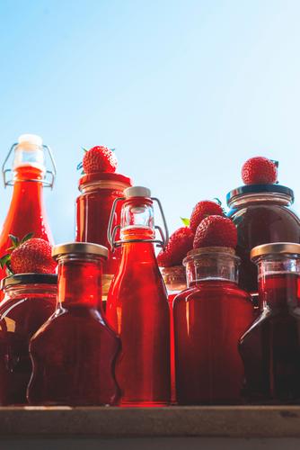 Glasflaschen und -gläser mit Erdbeersirup und Marmelade Container lecker Dessert Lebensmittel frisch Fruchtsirup Früchte satt Glaskolben Gesunder Lebensstil