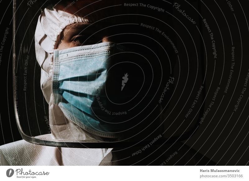 Heldenärztin mit Maske und Gesichtsschild weint Träne wegen Coronavirus covid-19 Atemschutzmaske schwarzer Hintergrund Blut Brasilien Klinik Korona-Epidemie