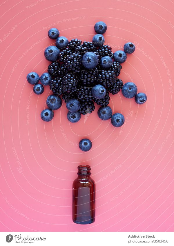 Frische Beeren und Glas auf rosa Hintergrund Flasche Blaubeeren Brombeeren frisch reif natürlich Gesundheit Lebensmittel Konzept Explosion trinken Dessert Saft