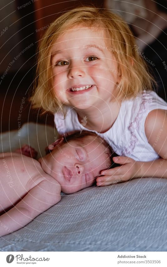 Glückliches kleines Mädchen streichelt mit Liebe Neugeborenes schläft zu Hause in weichem Bett neugeboren Streicheln Kind Schwester Säugling Windstille