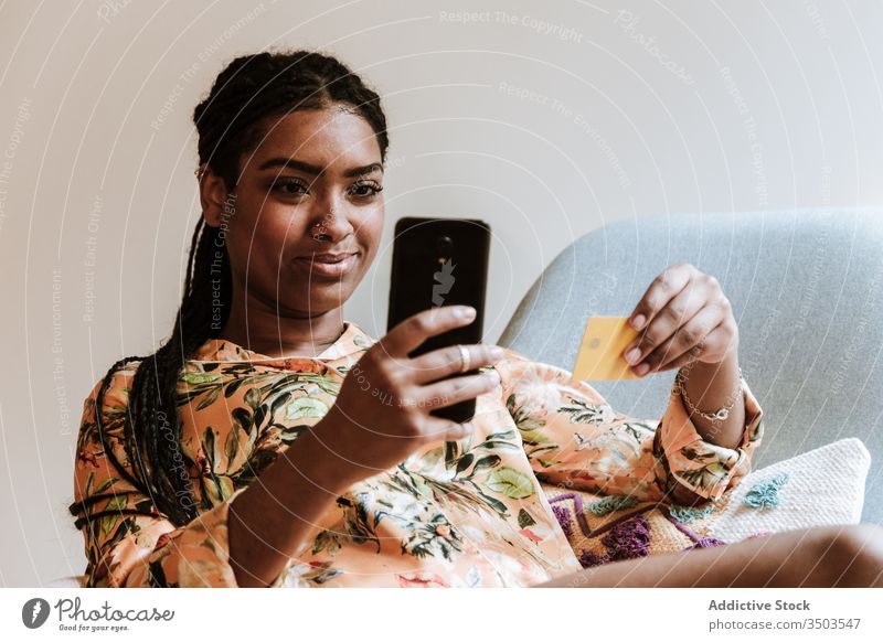Ethnische Frau, die zu Hause online einkauft Smartphone Kreditkarte Werkstatt Zahlung Kauf heimwärts benutzend Gerät Apparatur Lächeln Internet Käufer lässig
