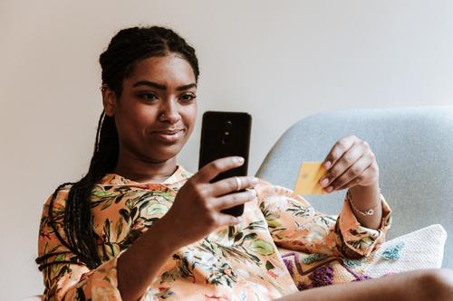 Ethnische Frau, die zu Hause online einkauft Smartphone Kreditkarte Werkstatt Zahlung Kauf heimwärts benutzend Gerät Apparatur Lächeln Internet Käufer lässig