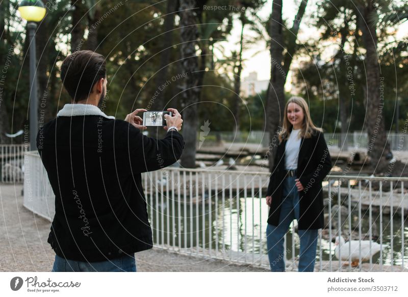 Mann fotografiert seine Freundin im Park Paar fotografieren Smartphone Großstadt Straße Apparatur Gerät Telefon Bildschirm Zusammensein Partnerschaft Lifestyle