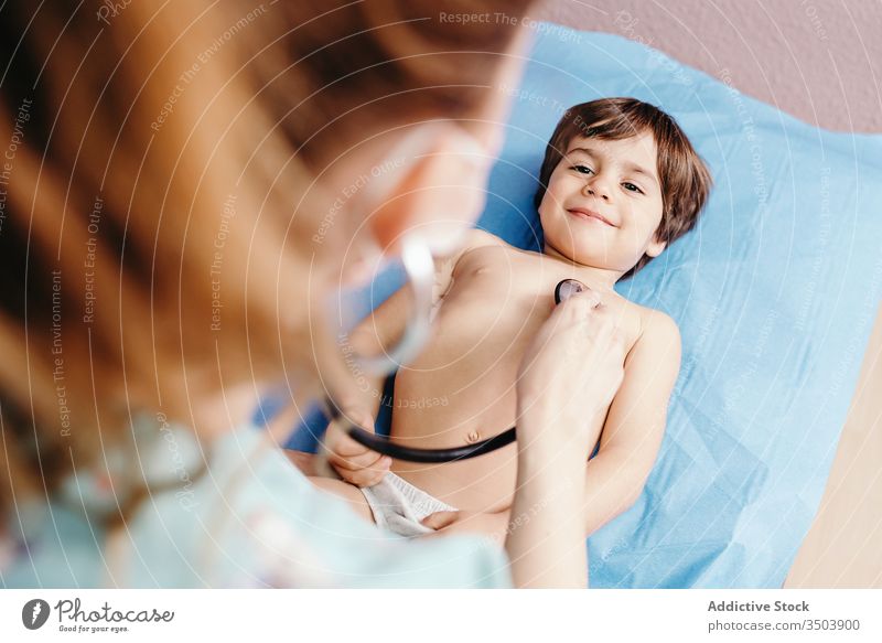 Arzt mit Stethoskop untersucht Kind in Klinik untersuchen heiter Lächeln Krankenhaus wenig Junge Lügen Liege Truhe Atemwegserkrankungen geduldig