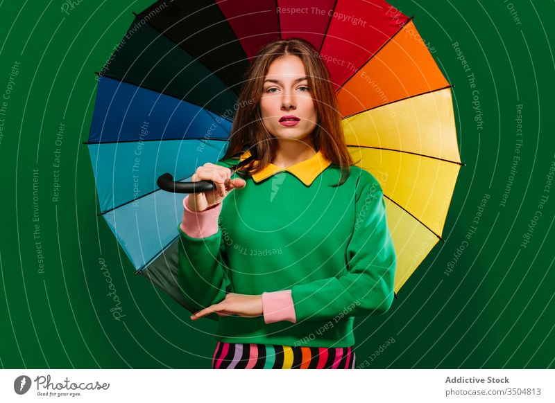 Junge Frau mit buntem Regenschirm im Studio farbenfroh Farbe Stil hell lebhaft jung mehrfarbig Mode Model emotionslos urban ernst selbstbewusst Accessoire