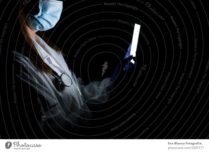 Ärztin im Haus, die ein Mobiltelefon benutzt. Tragen von Schutzhandschuhen, Maske und Stethoskop. Coronavirus covid-19-Konzept Frau Arzt Handy im Innenbereich