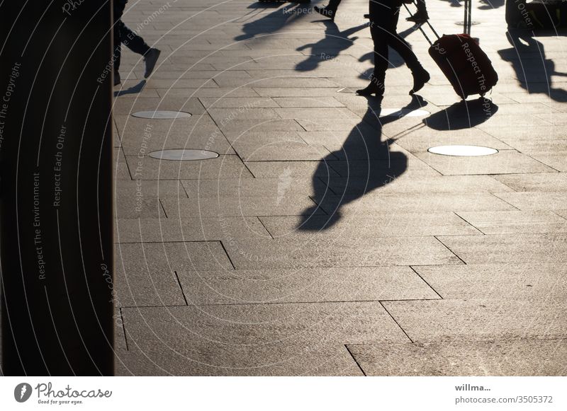 Reisende mit langen Schatten  und Rollkoffer auf dem Bahnhofsplatz Menschen Koffer gehen sonnig Menschengruppe verreisen Ferien & Urlaub & Reisen Flughafen