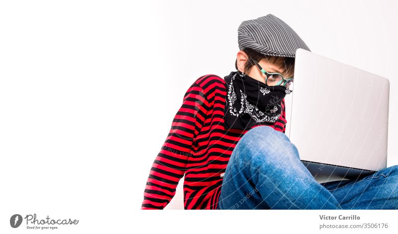 Süßer Junge mit Brille auf weißem Hintergrund mit einer Maske, der drinnen einen Laptop benutzt bezaubernd schön lässig heiter Kindheit Farbe Computer