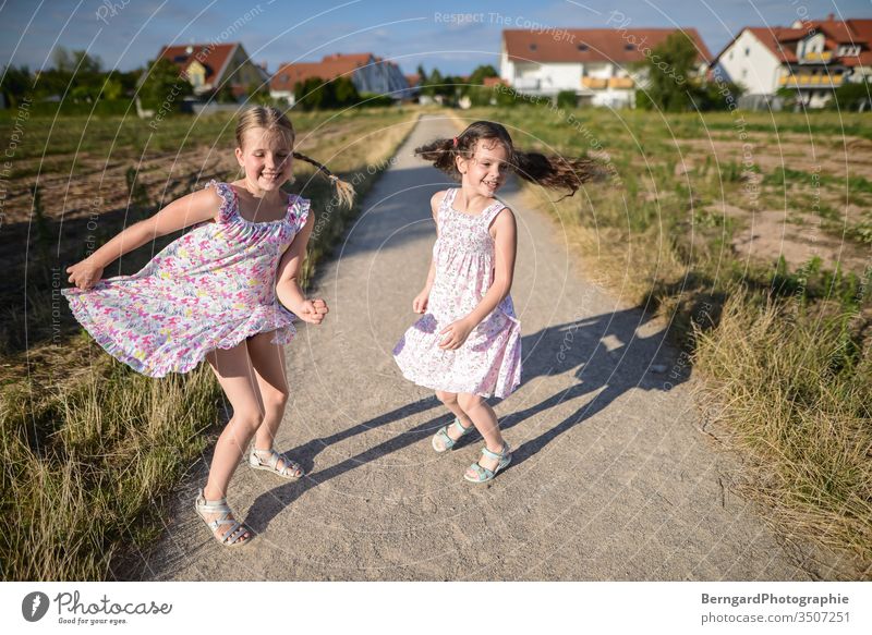 Two sisters play games summer sonne jumpin tanzen smiley happy schatten feld dorf girls kleid