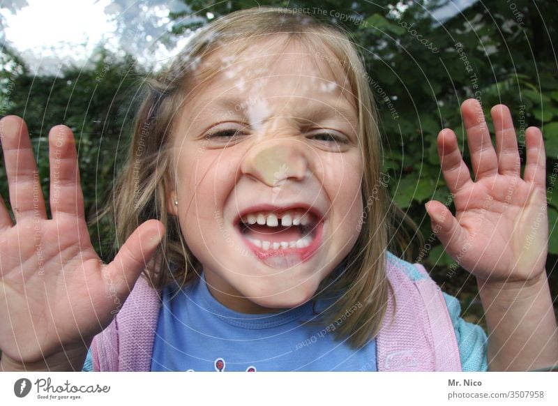 Kind hinter Glasscheibe Kindheit Spielen Freude platte Nase spass lustig Grimasse Grimassen schneiden Gesicht Mund Finger Zähne Zähne zeigen Fröhlichkeit frech