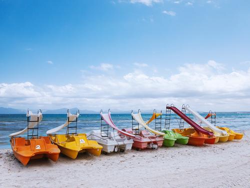 bunte Tretboote am Strand von Mallorca liegend Farbfoto Außenaufnahme mehrfarbig rot Tag orange grün gelb Menschenleer blau bunt gemischt Wasser Urlaub