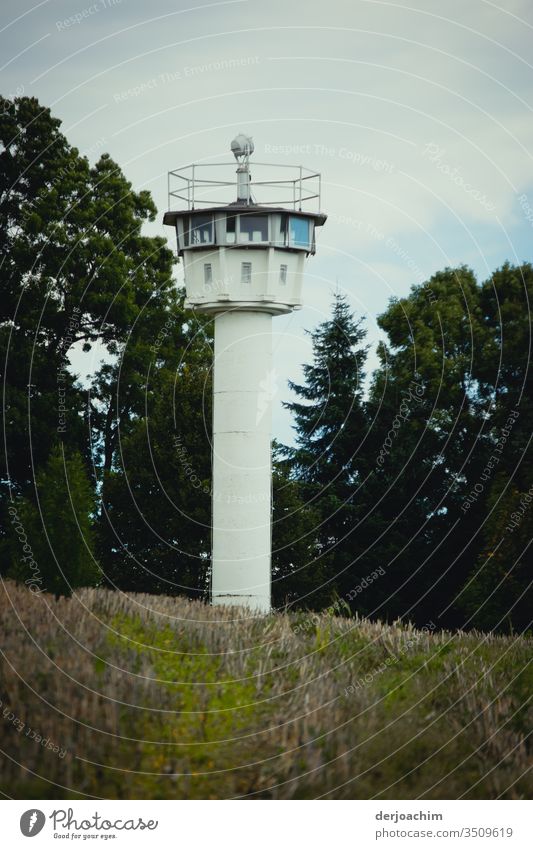 Zeitzeugen:Ein weißer Wachturm der DDR .Auf einer Wiese stehend. Im Hintergrund Bäume. Außenaufnahme Turm Farbfoto Menschenleer Denkmal Bauwerk Wahrzeichen