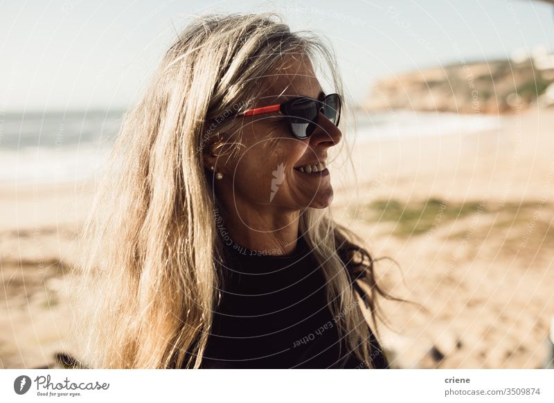 Glückliche ältere Frau mit Sonnenbrille am Strand Lächeln Strand-Sommer Senior älterer Erwachsener Freude Freizeit Urlaub