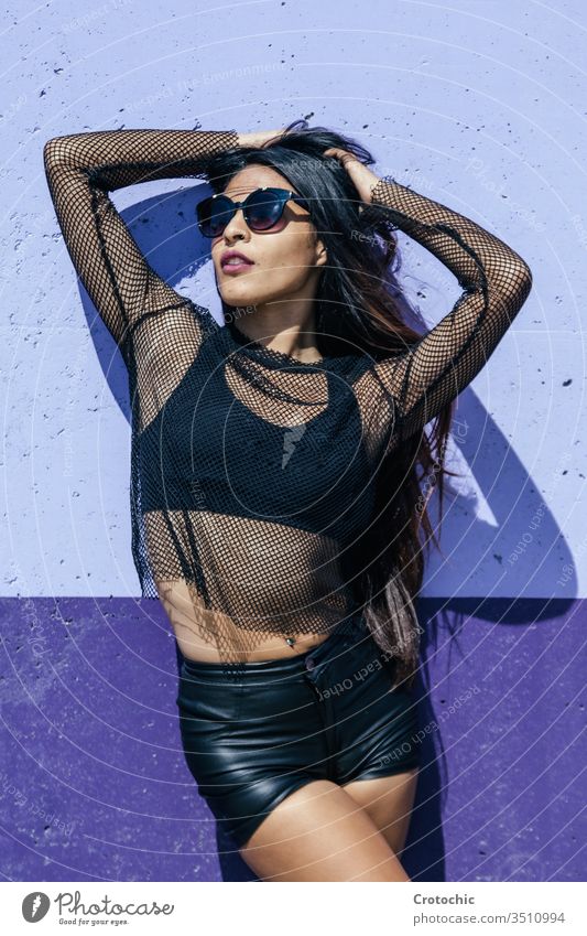 Brünettes Mädchen posiert als Model vor einer blauen Wand Farbe schwarz Reling ineinander greifen Sonnenbrille Sonnenbad Schönheit erotisch zierlich Tierhaut