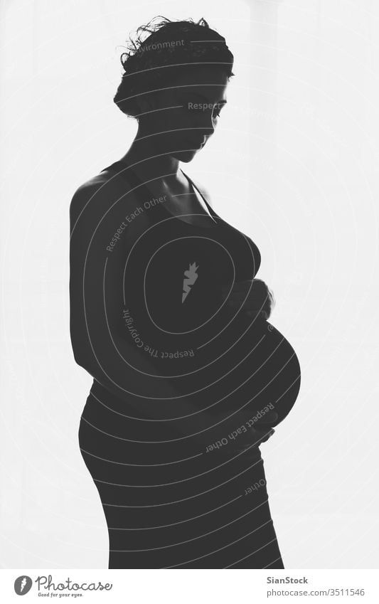 Schwangere Frau steht gegen das Fenster schwanger Schwangerschaft Bauch heimwärts Silhouette schön Glück Baby jung Leben Pflege Mutter schwarz bw Person