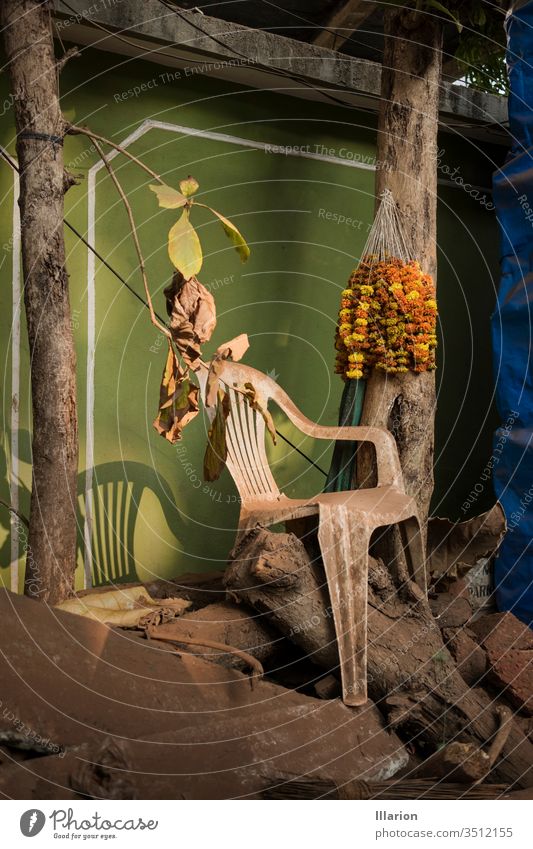 Verstaubter Plastikstuhl mit Blumendekoration auf dem Baum in der Nähe Kunststoff Menschenleer Stuhl Indien Blumenschmuck Staubwischen staubig Gestaubt