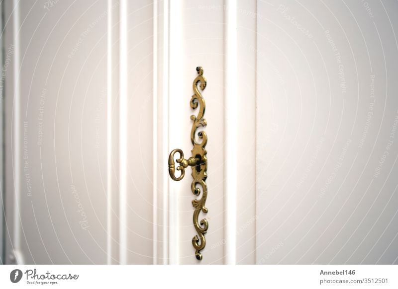Weiße Schranktüren mit goldenem Schlüssel im Schlüsselloch, luxuriöses antikes Design, Vintage-Holztüren in Nahaufnahme Haus Reichtum heimwärts Innenbereich
