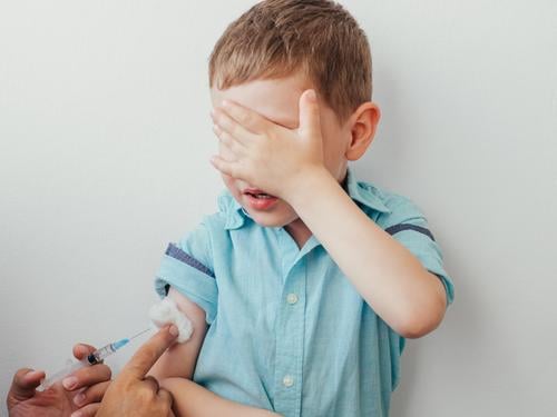Kleiner Junge hat Angst vor dem Impfen wenig ängstlich impfen Impfstoff Kaukasier Einspritzung Kind weiß bedeckt Auge blau Hemd Hand während Impfung Kinder
