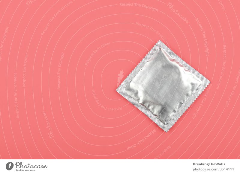 Nahaufnahme eines Kondompaketes über rosa Hintergrund Rudel Silber Folie umhüllen Pastell erhöht hoch Winkel Top Ansicht direkt oben Kopie Raum schließen