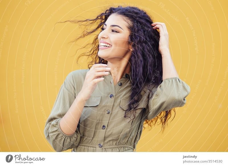 Arabische Frau mit lockigem, vom Wind bewegtem Haar Behaarung arabisch Frisur Lächeln schön Mädchen Schönheit jung eine Mode copyspace nahöstlich gelb grün