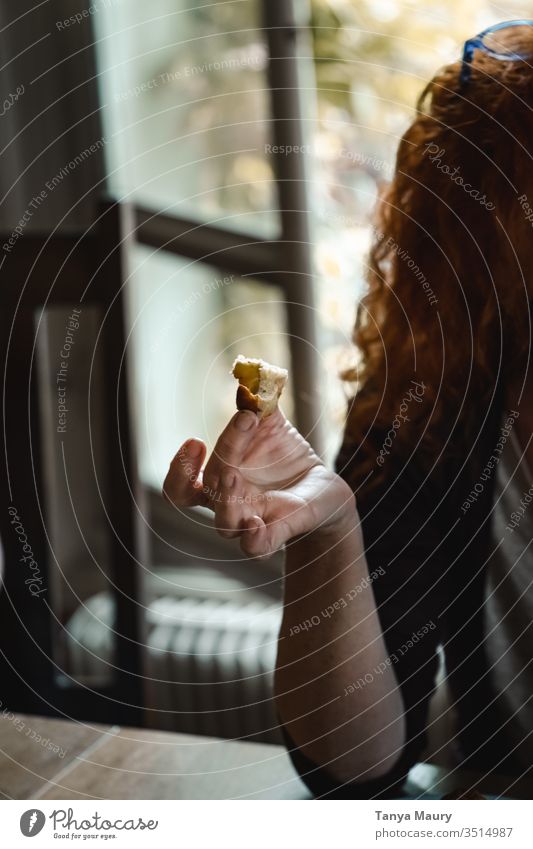 Frau isst ein Stück Kuchen Hand Essen Kinderspiel Spielfigur Ingwer-Kopf Brot Foodfotografie Menschen lockige Haare natürliches Licht im Innenbereich lecker