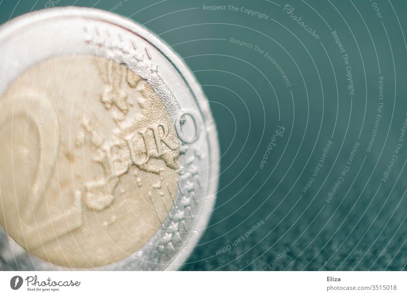 Nahaufnahme einer Zwei Euro Münze vor türkisem Hintergrund; Geld, Finanzen Makroaufnahme Eurostück hell Finazen Sparen Kapitalwirtschaft Geldmünzen Bargeld