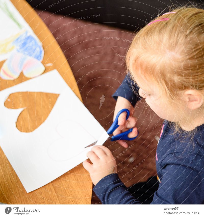 Mädchen schneidet mit einer Schere Herzen aus einem Blatt Papier aus Basteln Farbstifte Bemalen Kreativität ausschneiden Bastelnachmittag Farbfoto