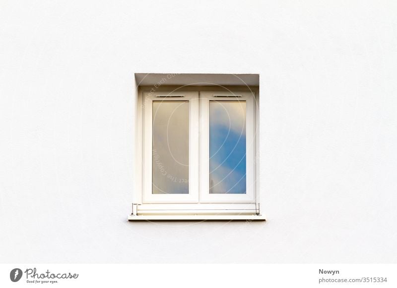 Geschlossenes weißes modernes Fenster an einer weißen Hauswand, die den blauen Himmel reflektiert Gebäudeaußenseite Sauberkeit übersichtlich abschließen