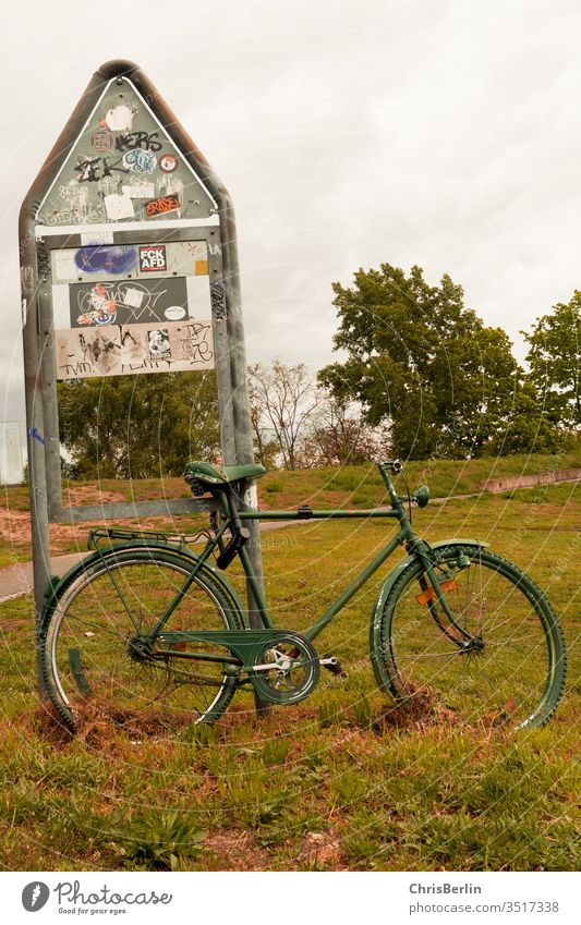 grünes Fahrrad angeschlossen an einem Schild Verkehrsschild Wiese abgestellt einsam Außenaufnahme Farbfoto Menschenleer Hinweisschild Sicherheit